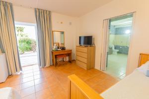 a bedroom with a bed and a television and a bathroom at Centre Algarve in Moncarapacho