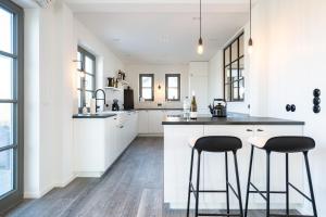a kitchen with white cabinets and black bar stools at Reetidyll am Haff - Haus 2 in Stolpe auf Usedom