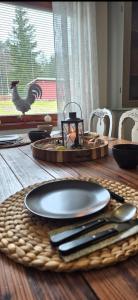 a table with plates and utensils and a chicken on the window at Monis und Marcos B&B in Koppom