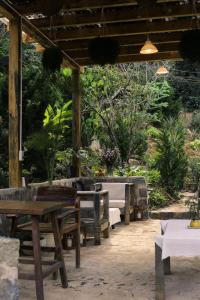 a patio with wooden tables and benches in a garden at À La Main Farmhouse in Ấp Trường Sơn