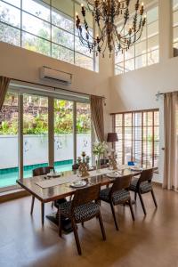 a dining room with a table and chairs and a chandelier at SaffronStays Forest Edge in Siolim