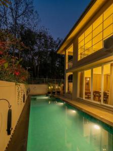 a swimming pool in front of a house at SaffronStays Forest Edge in Siolim