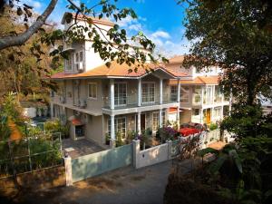 a large white house with a fence in front of it at SaffronStays Forest Edge in Siolim
