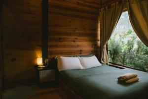 a bed in a wooden room with a window at À La Main Farmhouse in Ấp Trường Sơn