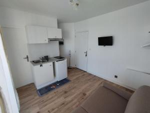 an empty white room with a kitchen and a television at Studio vue mer & accès direct à la plage in Le Barcarès