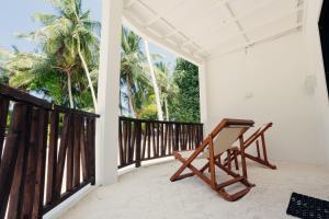a wooden bench sitting on a balcony with palm trees at Azul Retreat in Dhigurah