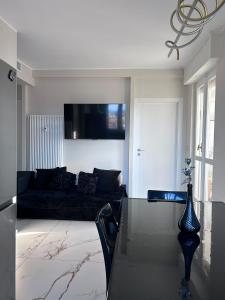 a living room with a black couch and a table at Camera da letto in Angolo di Pace in Grugliasco