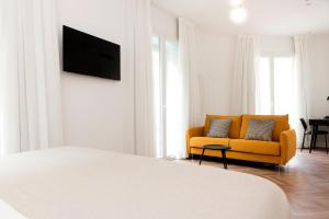 a living room with a yellow couch and a tv at Hotel Sauce in Zaragoza