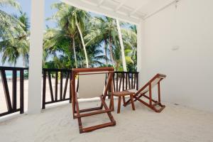 two wooden chairs sitting on a balcony with palm trees at Azul Retreat in Dhigurah +10 photos