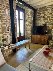 a living room with a stone wall with a tv at Dreamy Cottage in Ayiá