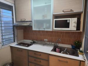 a kitchen with a sink and a microwave at The Greenway Sukhumvit 50 in Phra Khanong