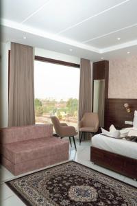 a bedroom with a bed and a couch and a window at The Aero Lounge Hotel 2kms From Airport in Amritsar