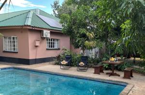 a house with a table and chairs next to a pool at Hungwe House in Victoria Falls