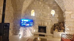 a stone room with a tv and a fireplace at Bayt Broud in Gharīfah +25 photos