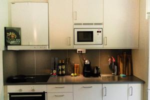 a kitchen with white cabinets and a microwave at Green Balcony Studio near Metro in Norsborg