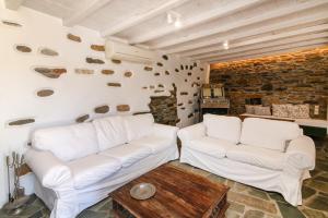 a living room with two white couches and a brick wall at Liostasi Tinos in Agios Fokas