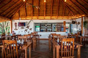 an empty restaurant with wooden tables and chairs at Telvina Beach Lodge in Vilanculos
