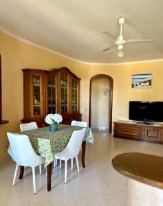 a dining room with a table and white chairs at Demetra Apartment Sperlonga in Sperlonga