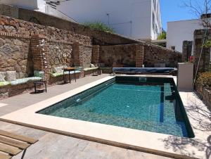 a swimming pool in front of a stone wall at Relax Ferrandiz in Málaga
