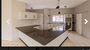 a kitchen with white cabinets and a black counter top at Elikia in Pretoria