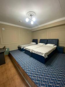 two beds in a room with a blue carpet at Shodlik Hostel in Andizhan