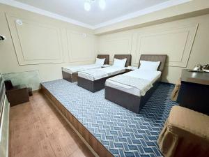a room with two beds and a blue rug at Shodlik Hostel in Andizhan