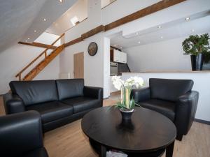 a living room with black leather couches and a table at 216 große Ferienwohnung Schwalbennest in Wittmund