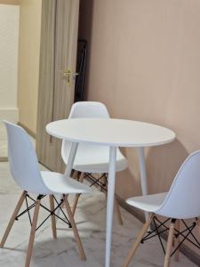 a white table and three white chairs in a room at Silver room 3 in Zatoka