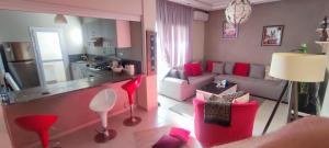 a living room with red furniture and a kitchen at Appartement Résidence fermée avec piscine in Ben Slimane
