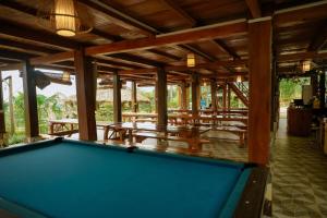 a pool table in a room with tables and benches at Mây farmstay in Ðà Bắc