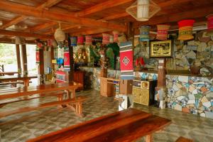 a restaurant with wooden benches in a room with tiles at Mây farmstay in Ðà Bắc