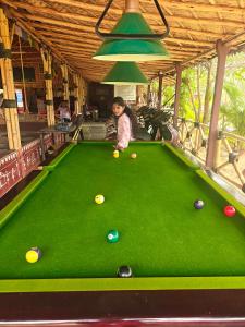 a young child playing pool on a pool table at Hampi Natures Cottage in New Hampi