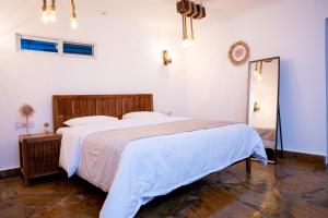a bedroom with a large bed with white sheets at Coast Sun Gardens Cottage Adults Only in Msambweni