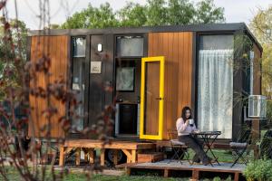 a woman sitting at a table in front of a tiny house at D&L Cottage by Tiny Away in Kudla