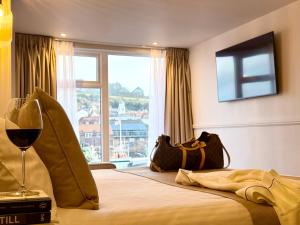 a hotel room with a bed with a glass of wine at Number 3 Pier Road Suites in Whitby +23 photos