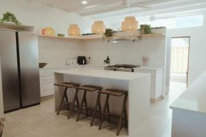 a kitchen with a white counter and bar stools at SeaWaves Beach House, Shelly Beach in Shelly Beach +36 photos