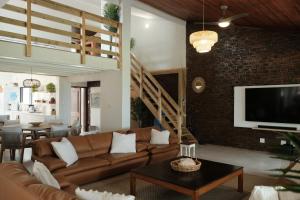 a living room with a brown couch and a tv at SeaWaves Beach House, Shelly Beach in Shelly Beach