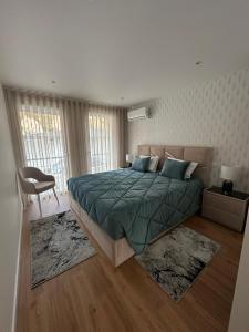 a bedroom with a bed with a green comforter and a chair at Apartamento AC T2 Pombal in Pombal +13 photos