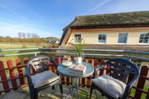 a table and chairs on a balcony with a house at Reethaus Boddenblick in Alt Reddevitz - Wohnung 4 in Mariendorf