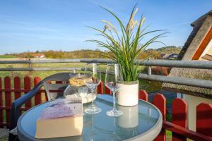 a glass table with wine glasses and a plant on a balcony at Reethaus Boddenblick in Alt Reddevitz - Wohnung 4 in Mariendorf