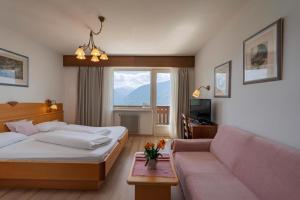 a hotel room with a bed and a couch at Panorama Hotel St Georgen in Schenna