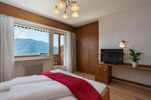 a bedroom with a large window and a bed and a television at Panorama Hotel St Georgen in Schenna