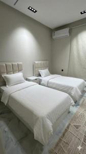 two beds in a bedroom with white sheets at فلة جديدة راقية بمسبح داخلي Luxury villa with indoor pool in Taif +21 photos