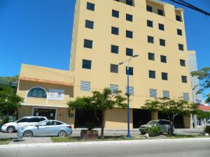 a tall yellow building with cars parked in front of it at Hotel Del Viajero in Ciudad del Carmen