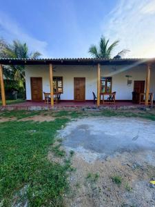 a white house with wooden doors and a yard at QUEEN SASTINA guest house in Nilaveli