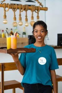 a young girl holding a wooden tray with a drink at Villa Bako Hôtel in Nosy Be +53 photos