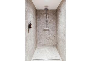 a shower in a bathroom with a stone wall at Goldvogel Apartments in Fischen +60 photos