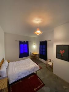 a bedroom with a white bed and a blue window at Hôtel bleu ciel in Aït Yous