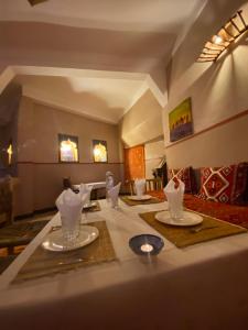 a dining room with a table with dishes on it at Hôtel bleu ciel in Aït Yous