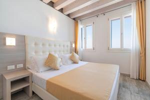 a bedroom with a large bed and two windows at Locanda Stravedo in Pellestrina